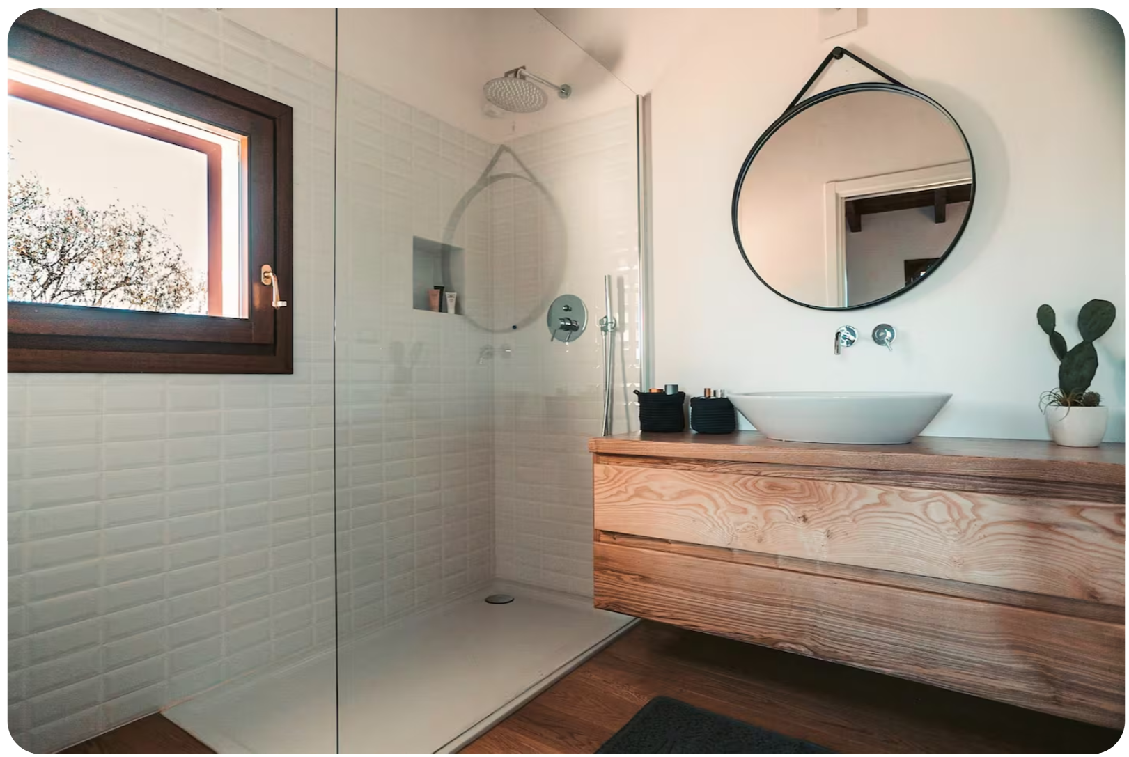 Bathroom with round mirror, white vessel sink, and wood vanity